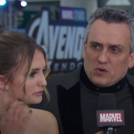Joe Russo is talking to a mic as Lia Mariella Russo listens.